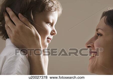 Stock Photo - Mother holding her sons head, close-up. Fotosearch