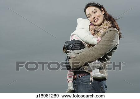 Stock Photo - Mother hugging sleeping baby, (portrait), (low angle view). Fotosearch
