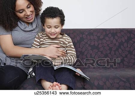 Stock Image - Mother reading book with son (5-6). Fotosearch
