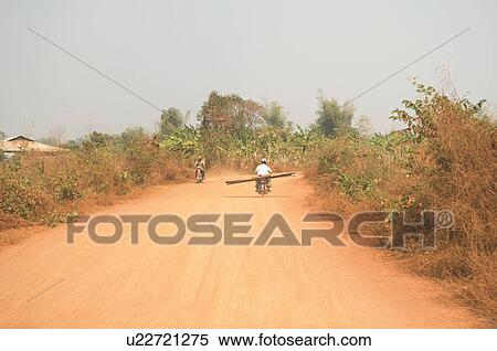 Stock Photography - Motorcycles on rural Dirt Road in Asia. Fotosearch