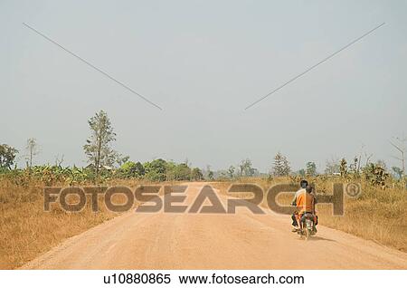 Stock Photography - Motorcyclist Giving Ride to Young Monk on Rural Road. Fotosearch