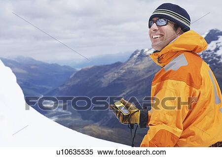 Stock Photography - Mountain climber holding compass in snowy mountains. Fotosearch
