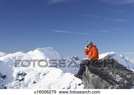 Stock Photo - Mountain climber using walkie-talkie on mountain peak. Fotosearch