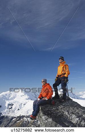 Stock Image - Mountain climbers on mountain peak. Fotosearch