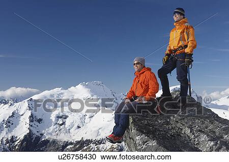 Stock Image - Mountain climbers on mountain peak. Fotosearch