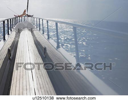 Stock Photo - Ocean reflected in side of yacht with woman sitting in background (low section). Fotosearch