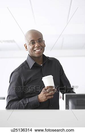 Picture - Office worker holding coffee cup in office. Fotosearch