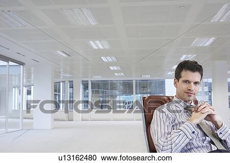 Office worker sitting in swivel chair, hands clasped, in empty office space View Large Photo Image Stock Image - Office worker sitting in swivel chair, hands clasped, in empty office space. Fotosearch