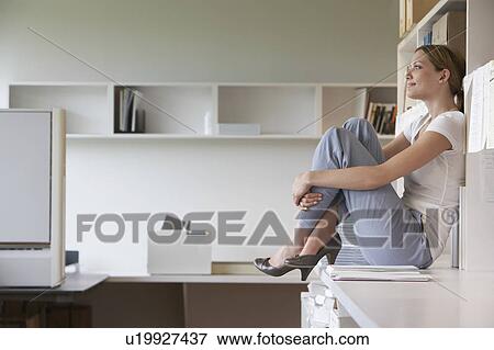 Office worker sitting on bench in office, side view View Large Photo Image Stock Photo - Office worker sitting on bench in office, side view. Fotosearch