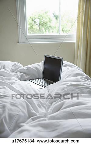 Picture - Open laptop lying on bed. Fotosearch