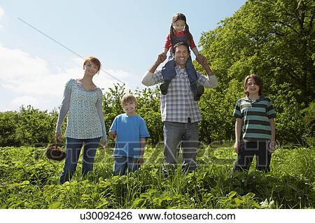 Stock Photograph - Parents and children (5-9) in strawberry field, portrait. Fotosearch