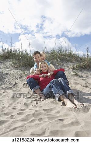 Parents and daughter (5-6) embracing on beach, portrait View Large Photo Image Picture - Parents and daughter (5-6) embracing on beach, portrait. Fotosearch