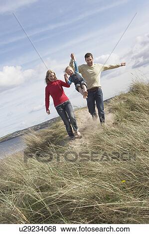 Parents lifting daughter (5-6) on sand dunes View Large Photo Image Stock Photo - Parents lifting daughter (5-6) on sand dunes. Fotosearch