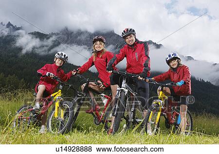Stock Photo - Parents with children (7-9) on bikes in countryside, portrait. Fotosearch