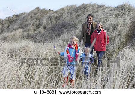 Parents with two children (3-6) walking in long grass View Large Photo Image Stock Image - Parents with two children (3-6) walking in long grass. Fotosearch