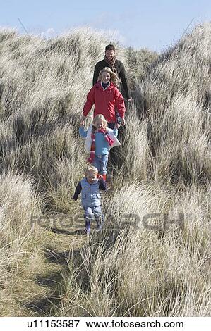 Stock Photo - Parents with two children (3-6) walking in long grass. Fotosearch