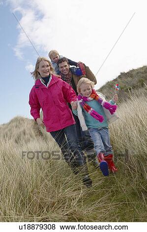 Parents with two children (3-6) walking in long grass View Large Photo Image Stock Photo - Parents with two children (3-6) walking in long grass. Fotosearch