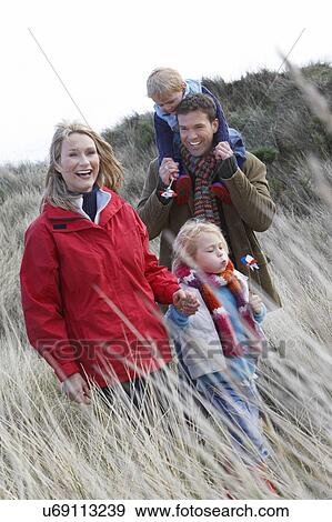 Stock Photo - Parents with two children (3-6) walking in long grass. Fotosearch