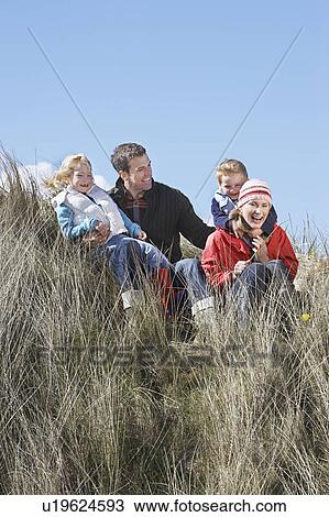 Stock Image - Parents with two children (4-6) sitting in grass. Fotosearch