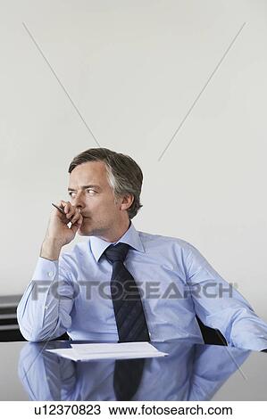 Stock Image - Pensive business man working at conference table. Fotosearch