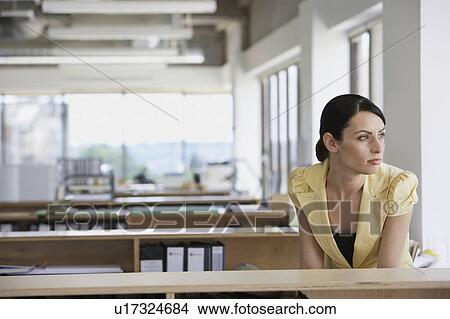 Picture - Pensive woman sitting at desk in office. Fotosearch