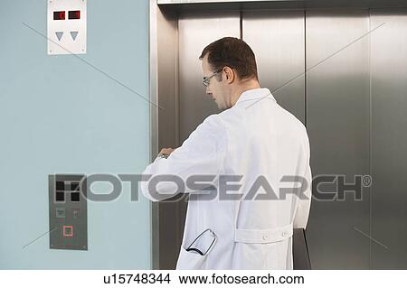 Physician Checking His Watch by elevator View Large Photo Image Picture - Physician Checking His Watch by elevator. Fotosearch