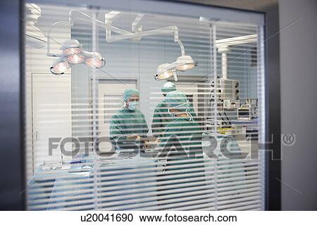 Stock Image - Physicians in Surgery, viewed through window. Fotosearch