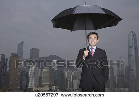Stock Photo - Portrait of business man with umbrella, smiling. Fotosearch