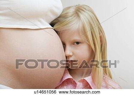 Stock Photograph - Portrait of girl (7-9) leaning on pregnant mother's belly. Fotosearch