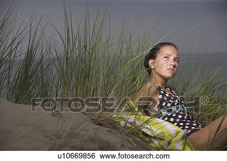 Stock Photograph - Portrait of girl on sand dune with sea in background. Fotosearch