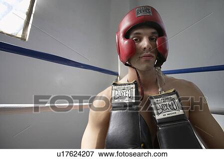 Stock Photo - Portrait of man wearing head protector in boxing ring. Fotosearch