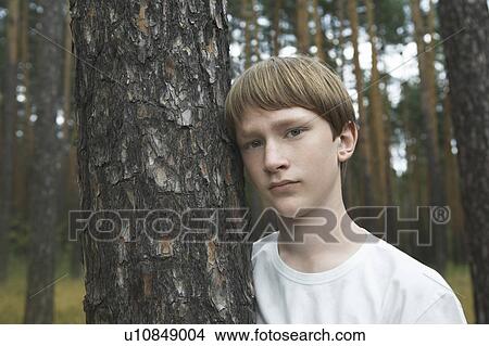 Picture - Portrait of teenage boy standing at tree. Fotosearch