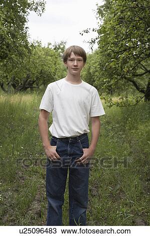 Stock Image - Portrait of teenage boy standing in field. Fotosearch