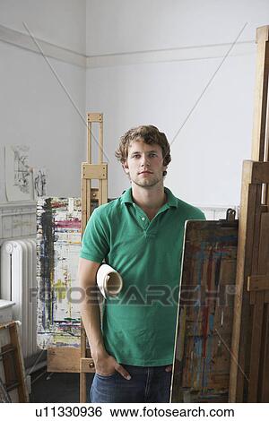 Stock Photograph - Portrait of young male artist in art studio. Fotosearch