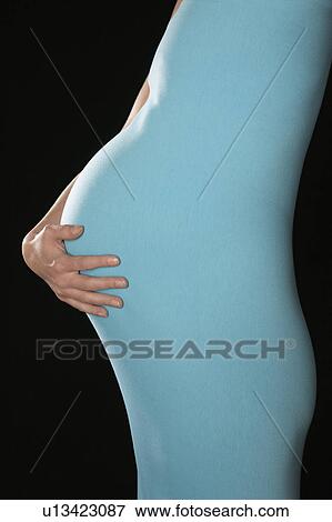 Pregnant woman in body suit holding abdomen, mid section, side view, studio shot View Large Photo Image Stock Photo - Pregnant woman in body suit holding abdomen, mid section, side view, studio shot. Fotosearch
