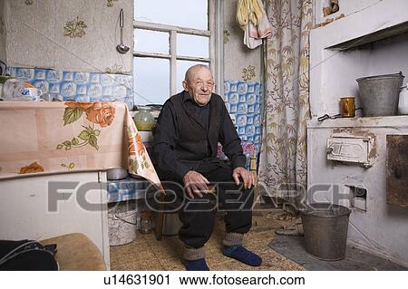 Stock Image - Russia, senior man sitting in kitchen. Fotosearch