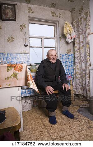 Stock Image - Russia, senior man sitting in kitchen. Fotosearch