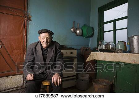 Stock Photo - Russia, senior man sitting in kitchen. Fotosearch