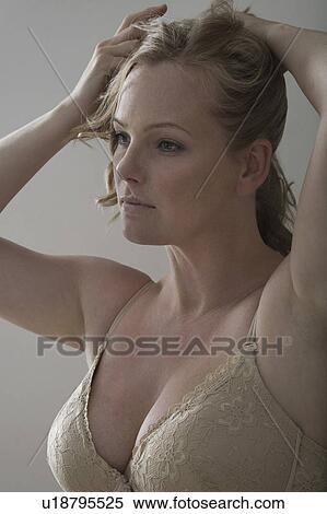 Stock Photography - Semi-dress mid adult woman tying her hair. Fotosearch