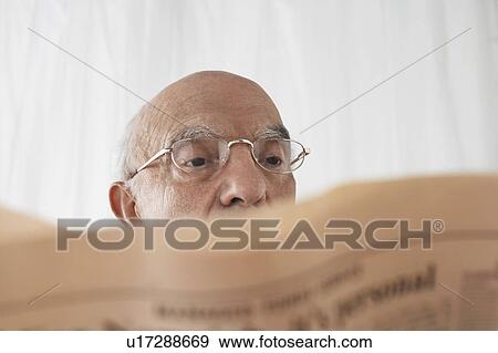 Stock Photo - Senior man in spectacles reading newspaper, close up. Fotosearch