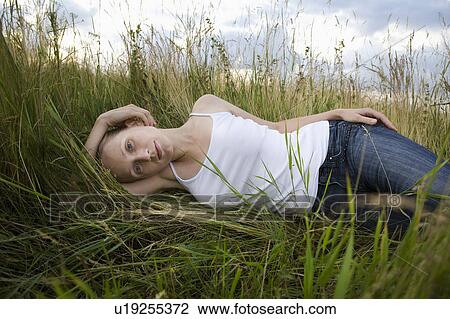 Serene young woman resting in meadow View Large Photo Image Stock Image - Serene young woman resting in meadow. Fotosearch