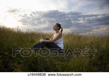 Stock Photo - Serene young woman sitting in meadow. Fotosearch