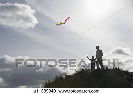 Silhouette of girl and father flying kite on dunes View Large Photo Image Stock Image - Silhouette of girl and father flying kite on dunes. Fotosearch