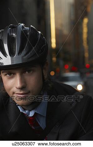 Stock Photo - Smiling man wearing cycling helmet on street, close-up, portrait. Fotosearch