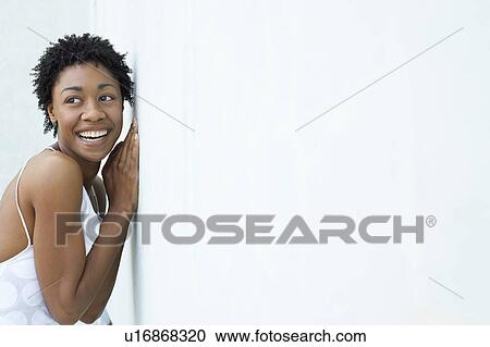 Stock Image - Smiling woman leaning against wall, portrait. Fotosearch