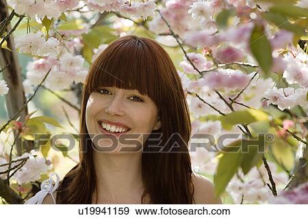 Stock Photo - Smiling Young Woman by Fruit Tree. Fotosearch