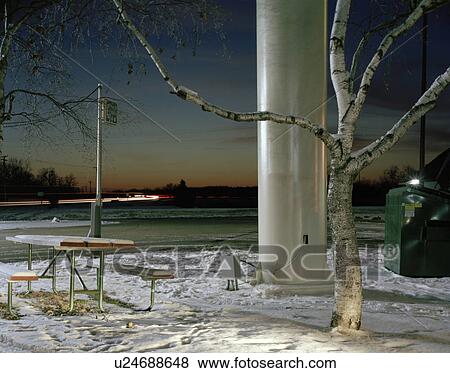 Stock Photo - Snowy picnic table next to parking lot at night. Fotosearch