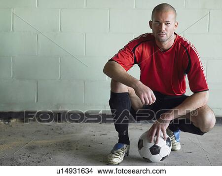 Picture - Soccer player crouching with ball, portrait. Fotosearch