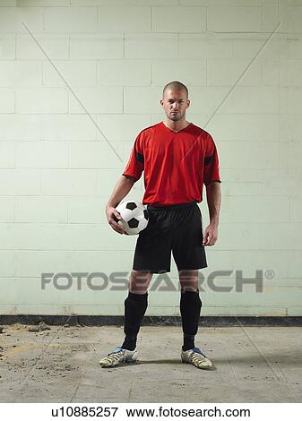 Stock Photo - Soccer player holding ball, portrait. Fotosearch