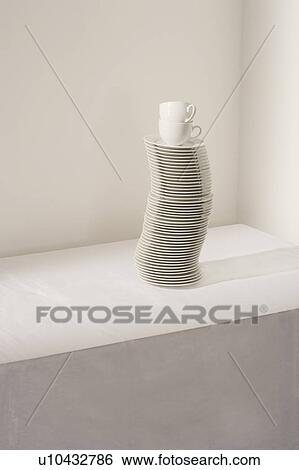 Stock Photograph - Stack of plates and cups on table, elevated view. Fotosearch